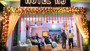 Entrada de hotel decorada con arreglos florales y un letrero que dice "HOTEL RJ".