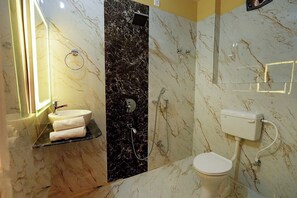 A bathroom with a marble sink, a toilet, and a shower.