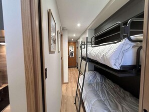 A narrow hallway with bunk beds on one side and a wooden door on the other.