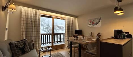 A cozy living room with a sofa, a dining table, and a kitchen area.
