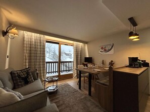 A cozy living room with a sofa, a dining table, and a kitchen area.