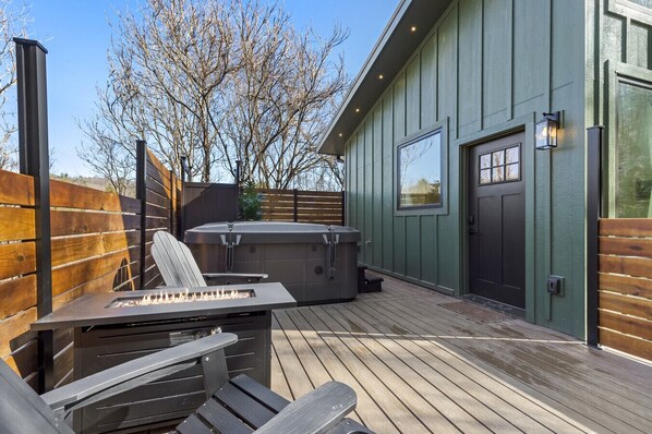Una terraza con jacuzzi, fogata y asientos al aire libre.