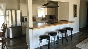 A modern kitchen with a central island, bar stools, a refrigerator, and a microwave. - Sleeps 10. Bayou Front Home close to ULM, Sports Complexes, Airport and I-20. (Monroe)