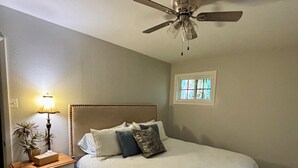 A bedroom with a bed, a nightstand, a lamp, a ceiling fan, and a window. - Sleeps 10. Bayou Front Home close to ULM, Sports Complexes, Airport and I-20. (Monroe)