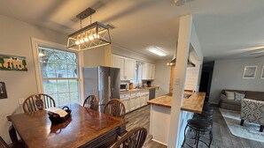 A spacious kitchen with a dining area, wooden flooring, and a modern pendant light. - Sleeps 10. Bayou Front Home close to ULM, Sports Complexes, Airport and I-20. (Monroe)