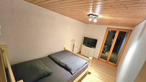 Ein Schlafzimmer mit einem Bett, einem Fernseher und einer Schiebetür.