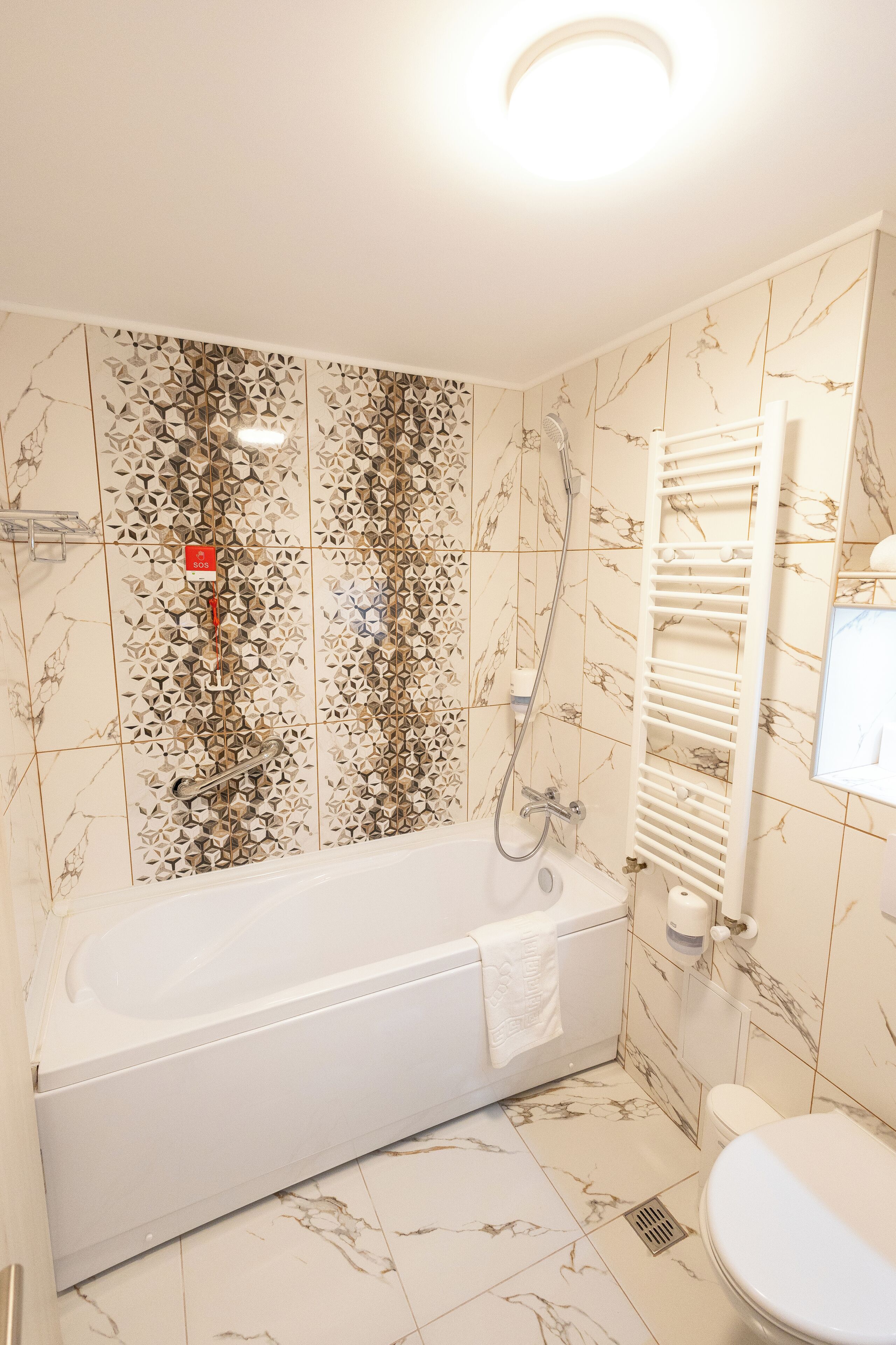 A bathroom with a white bathtub, a toilet, and a shower area.