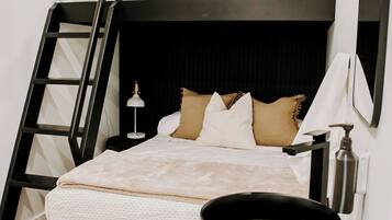A bunk bed with a ladder, a bedside table with a lamp, and a mirror.