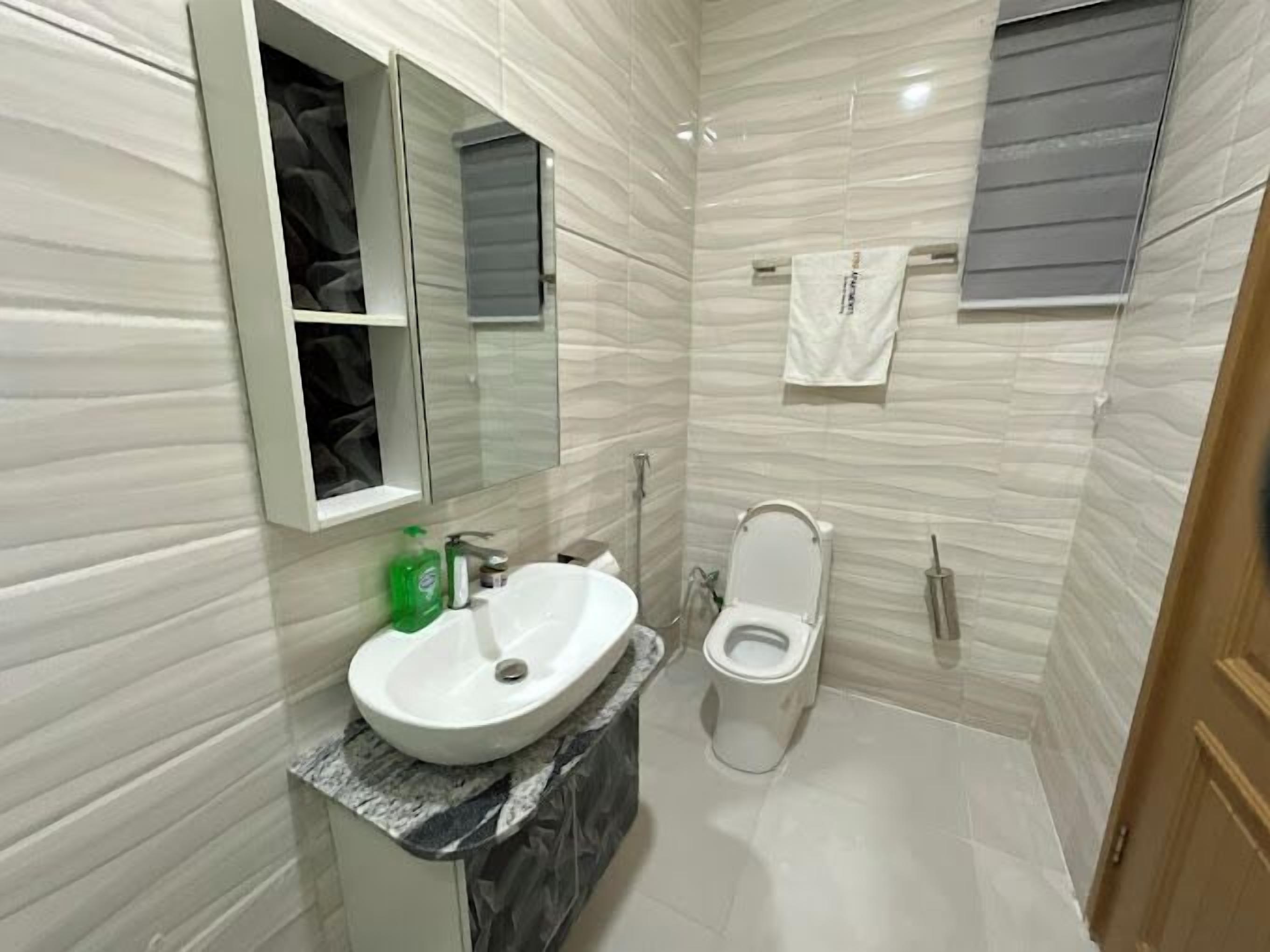 Casa de banho com lavatório branco, sanita e espelho.