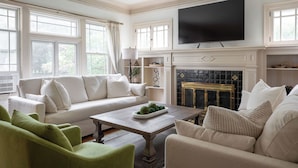 Un salon avec un canapé blanc, des fauteuils verts, une table basse et une cheminée.