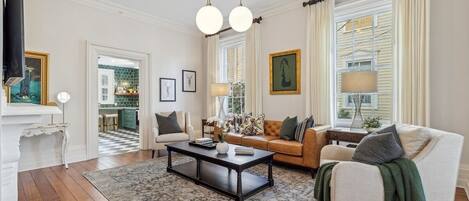 A living room with a wooden floor, a coffee table, a sofa, and a television.