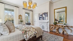 A bedroom with a large bed, a chandelier, a fireplace, and a mirror with a wooden frame. - Palazzo Sul Monte-Uno (Wilmington)