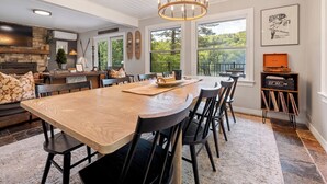 Une salle à manger spacieuse avec une longue table en bois, des chaises noires et un lustre.