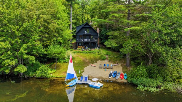 Un chalet au bord du lac, doté d’une terrasse et entouré d’une forêt dense.