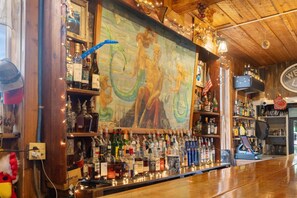 A bar area with a wooden ceiling, a mural, and shelves stocked with various liquor bottles. - The Downtown Historic Island Hotel (Cedar Key)