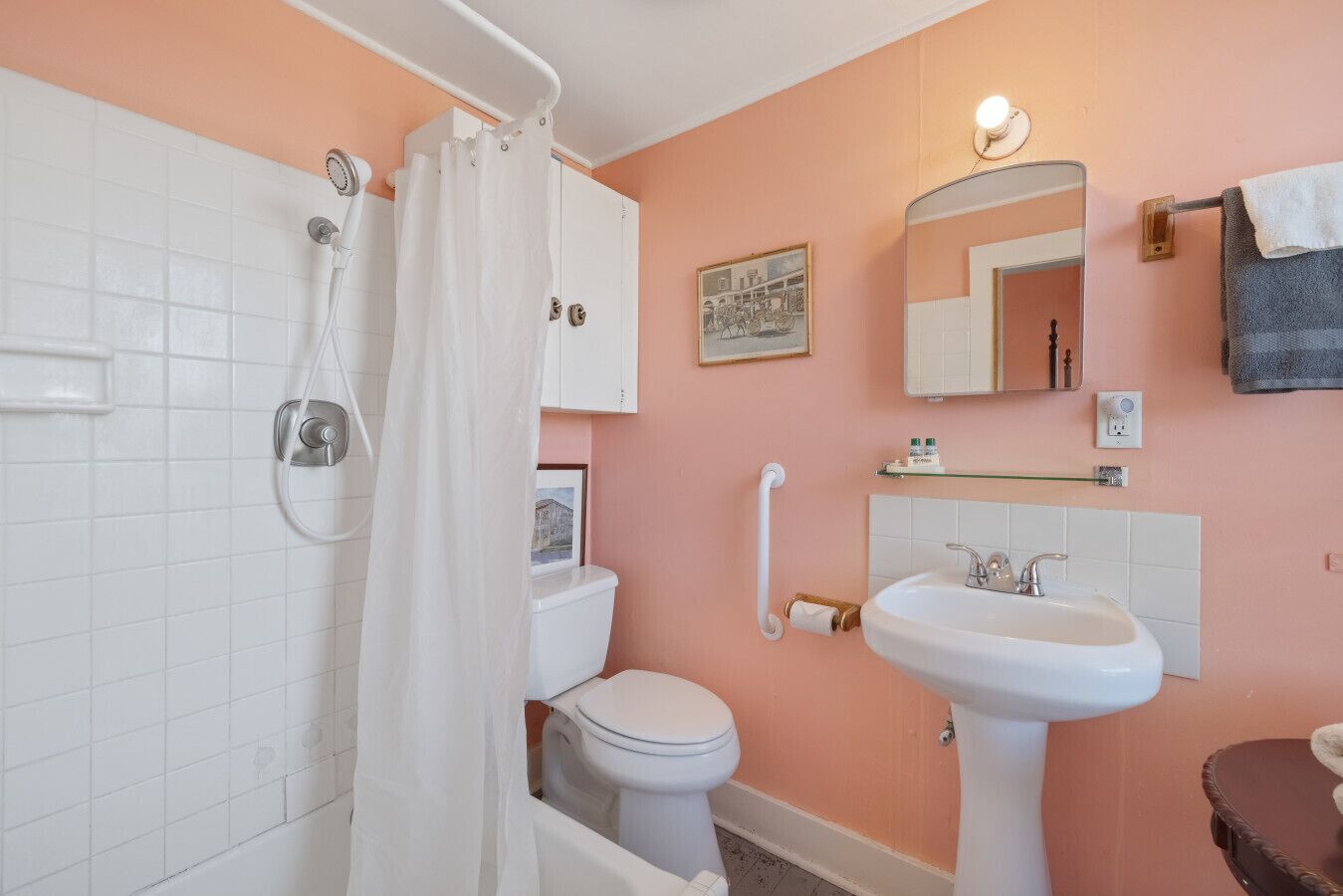 Een badkamer met douche, toilet, wastafel en een spiegel.