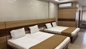 A hotel room with two beds, a ceiling fan, an air conditioning unit, and a view of the outside through a window. - DWC Residency (Kanchipuram)