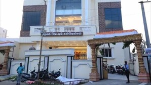 A multi-story building with a large central entrance, a signboard above the entrance, and a covered area with a statue in front. - DWC Residency (Kanchipuram)