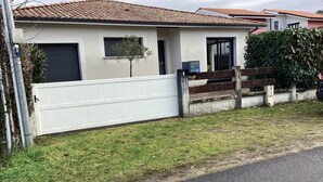 A single-story house with a tiled roof, a white exterior, and a fenced yard.