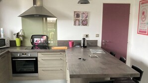 A modern kitchen with a central island, stainless steel appliances, and bar stools.