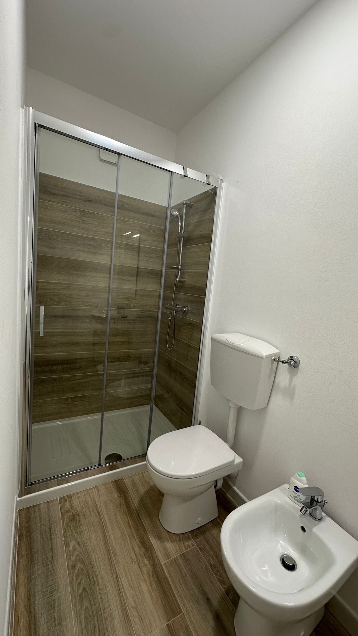 Une salle de bain avec une douche à parois de verre, des toilettes et un lavabo.