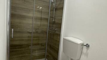 Une salle de bain avec une douche à parois de verre, des toilettes et un lavabo.