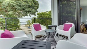 A balcony with white chairs and a small table, overlooking a body of water and greenery. - Take Two! Private Beach House! (Placencia Village)