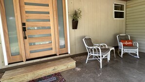 A wooden door with glass panels, a welcome mat, two wicker rocking chairs, and a small window. - Retro Cottage Farmstay
Mid-term Comfort for Family Relocations/Professionals (Newton)