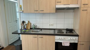 A kitchen with wooden cabinets, a stainless steel sink, a stove, and an oven. - Centrally located, small apartment with kitchen and shower room 2 (Hamburg)