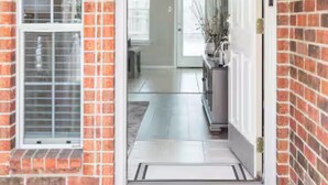 Une maison en briques avec une porte blanche et un paillasson.