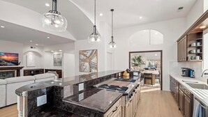 A modern kitchen with a large island, pendant lighting, and a view to the dining area. - Scenic Luxury Oasis: Views, Pool, Spa, Game & Movie Rms (Bonita)