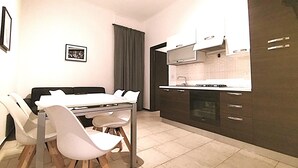 A compact kitchen with a dining area, featuring a modern design with dark cabinets and a white countertop. - HH Monferrato (Alessandria)