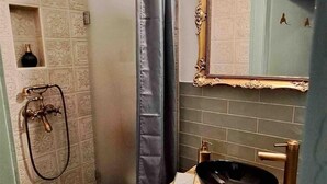 A bathroom with a shower, a sink with a black basin, and a mirror with an ornate frame. - KK30 Apartment (Budapest)