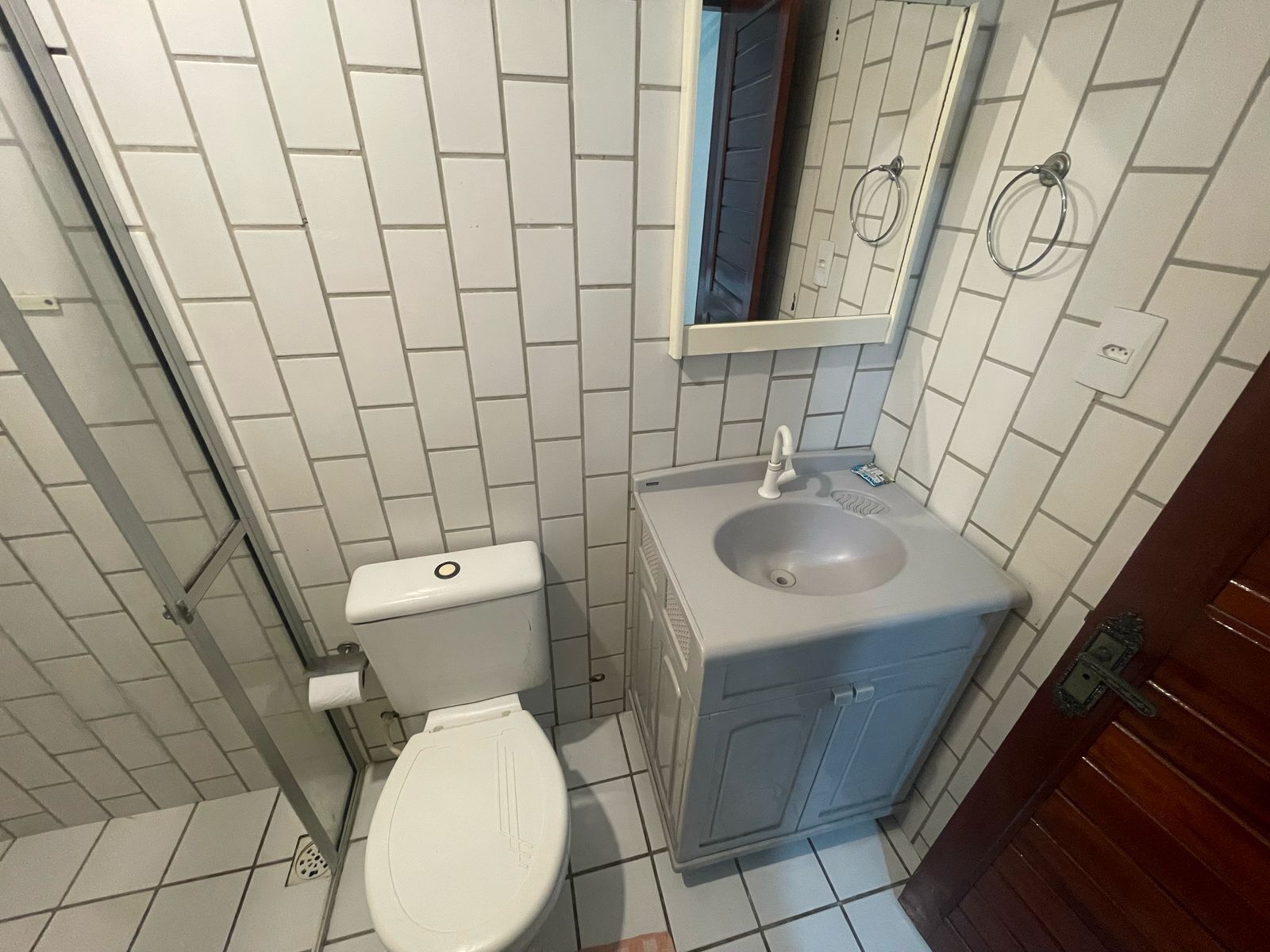 A small bathroom with a toilet, sink, and mirror.