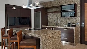 Una cocina moderna con encimeras de granito, electrodomésticos de acero inoxidable, horno empotrado y un televisor de pantalla plana.