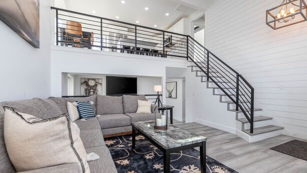 A spacious living room with a gray sectional sofa, a coffee table, and a staircase leading to an upper level. - Cottonwood Basecamp-Game Room, 6TVS, Near Canyons! (Sandy)