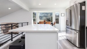 A modern kitchen with a large island, stainless steel appliances, and a view of mountains through large windows. - Cottonwood Basecamp-Game Room, 6TVS, Near Canyons! (Sandy)