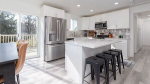 A modern kitchen with white cabinetry, stainless steel appliances, and a large island with bar stools. - Cottonwood Basecamp-Game Room, 6TVS, Near Canyons! (Sandy)