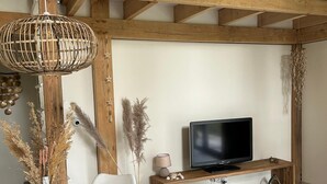A modern living room with a wooden dining table, white chairs, a TV on a wooden stand, and a staircase with wooden railings. - Oak Chalet In Zutendaal (Zutendaal)
