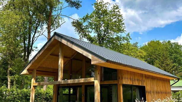 A modern wooden house with a covered patio, large windows, and a well-maintained garden. - Oak Chalet In Zutendaal (Zutendaal)