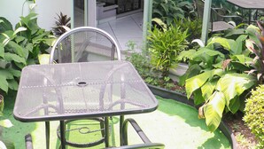 A patio with a metal table and chairs, surrounded by various potted plants and a glass door leading to an indoor area. - Motel Caribe (Córdoba)