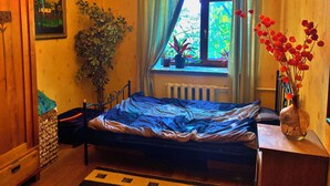 A bedroom with a bed, a radiator, a window with curtains, a potted plant, and a vase with flowers. - Apartment with free parking in central Tallinn (Tallinn)