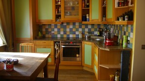 A kitchen with wooden cabinets, a tiled backsplash, and a dining area with a table and chairs. - Apartment with free parking in central Tallinn (Tallinn)