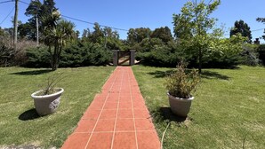 A paved pathway leading to a gated entrance surrounded by lush greenery and potted plants. - Amazing Home in Bella!!!Beautiful views, peace, and everything you need to enjoy (Bella Vista)
