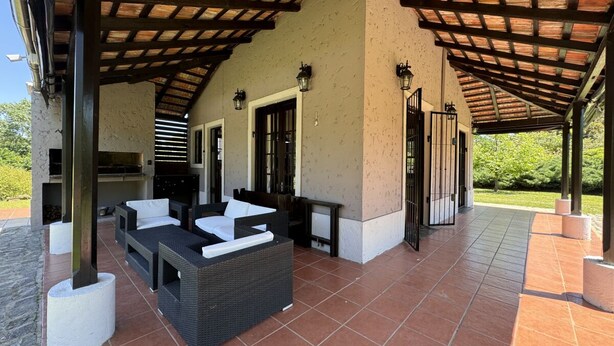 An outdoor patio area with a covered seating area, a grill, and a view of greenery. - Amazing Home in Bella!!!Beautiful views, peace, and everything you need to enjoy (Bella Vista)