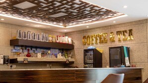 Eine Kaffeebar mit Theke aus Holz, Regalen für Kaffeizubehör und einem Schild über der Theke.