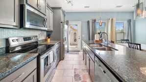 Una cocina moderna con electrodomésticos de acero inoxidable, encimeras de granito y una isla grande con un lavamanos.
