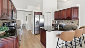 Una cocina moderna con armarios de madera oscura, electrodomésticos de acero inoxidable y una isla central con taburetes de bar.