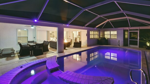 Una piscina con un porche techado, mobiliario exterior e iluminación geométrica en el techo.