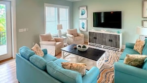Una sala de estar con sofás color turquesa, una mesa de centro y un televisor.